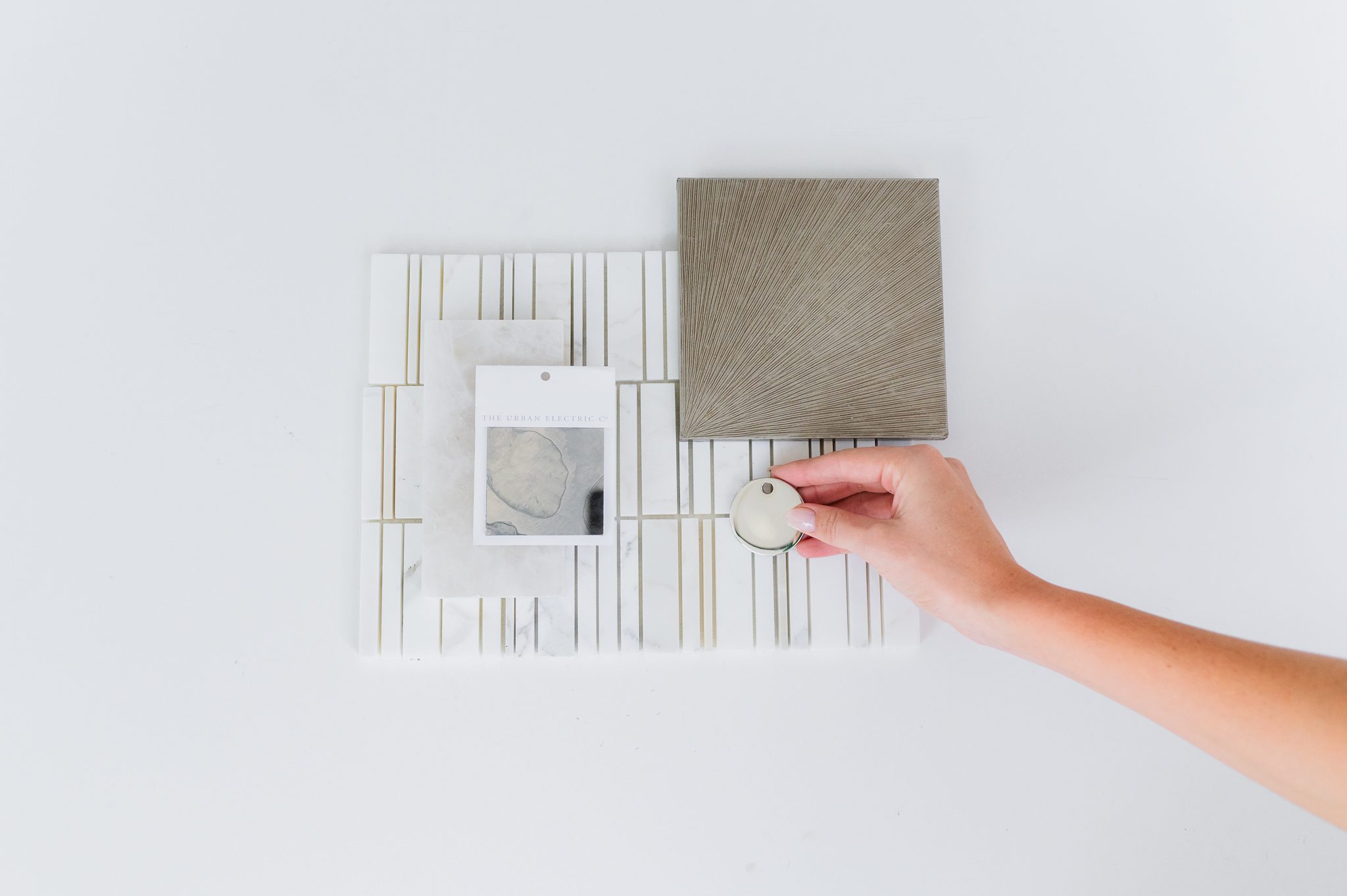 Flat lay of marble tile, textured panels, and hardware curated for an interior design project.